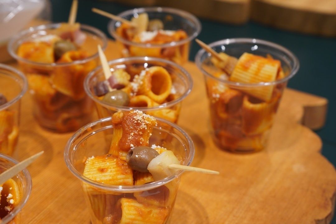 Gläser mit italienisch anmutendem Pasta-Fingerfood auf einem Holzbrett