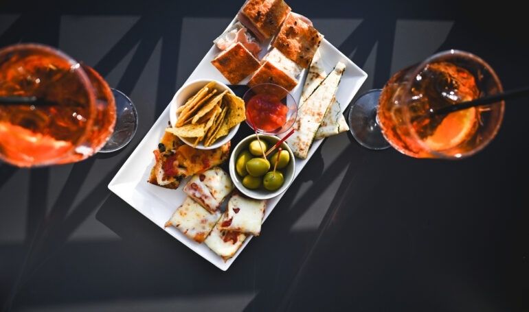 Aperitivo-Platte mit Snacks, Oliven und zwei orangefarbenen Drinks