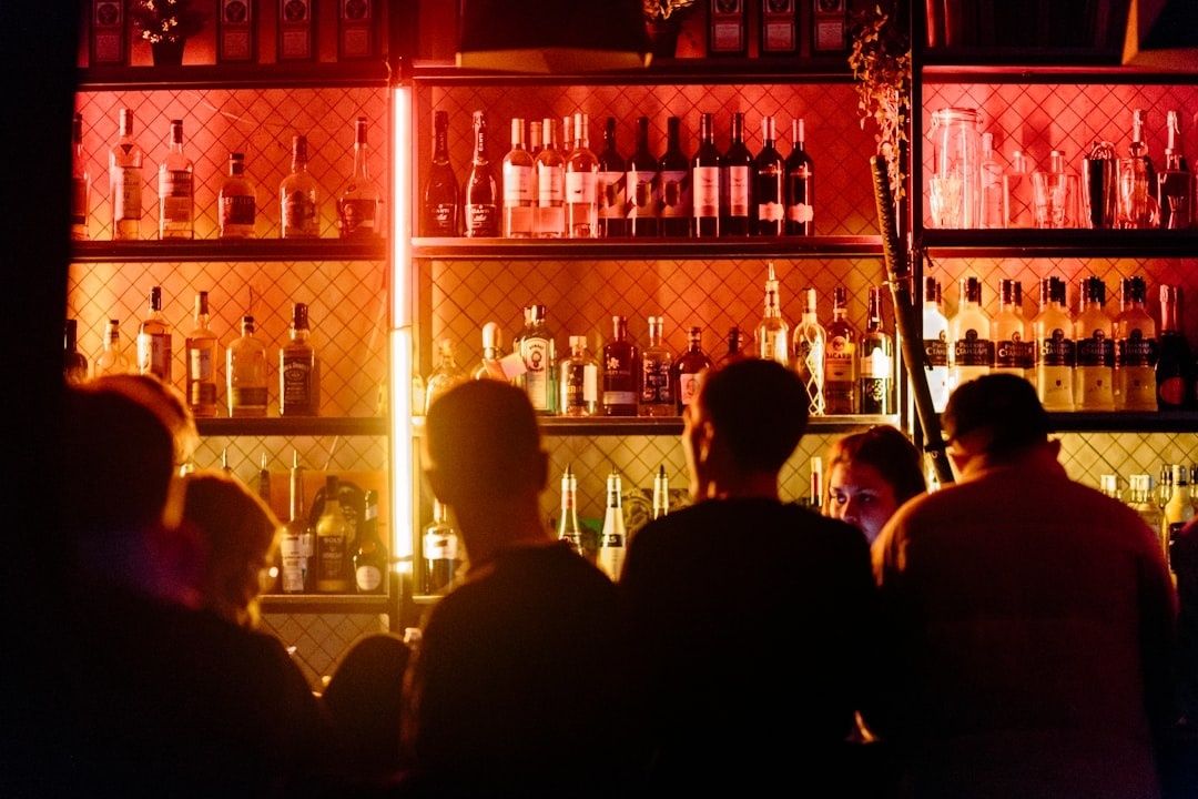 Gedämpft beleuchtete Bar mit Gästen vor Regalen voller Spirituosen