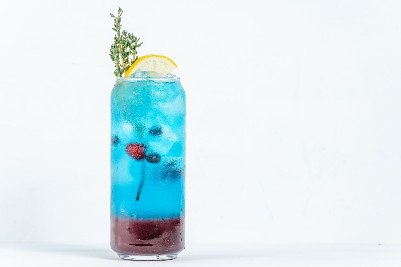 Alkoholfreier blauer Drink mit Eis, Zitrone, Beeren und Kräutern