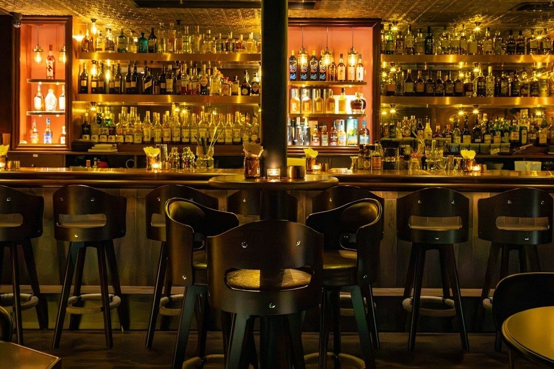 Stilvolle, dämmrige Bar mit Spirituosenregalen und vielen Sitzplätzen