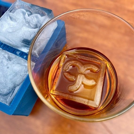 Bernsteinfarbener Drink mit klarem, handgeschnittenem Eiswürfel im Glas
